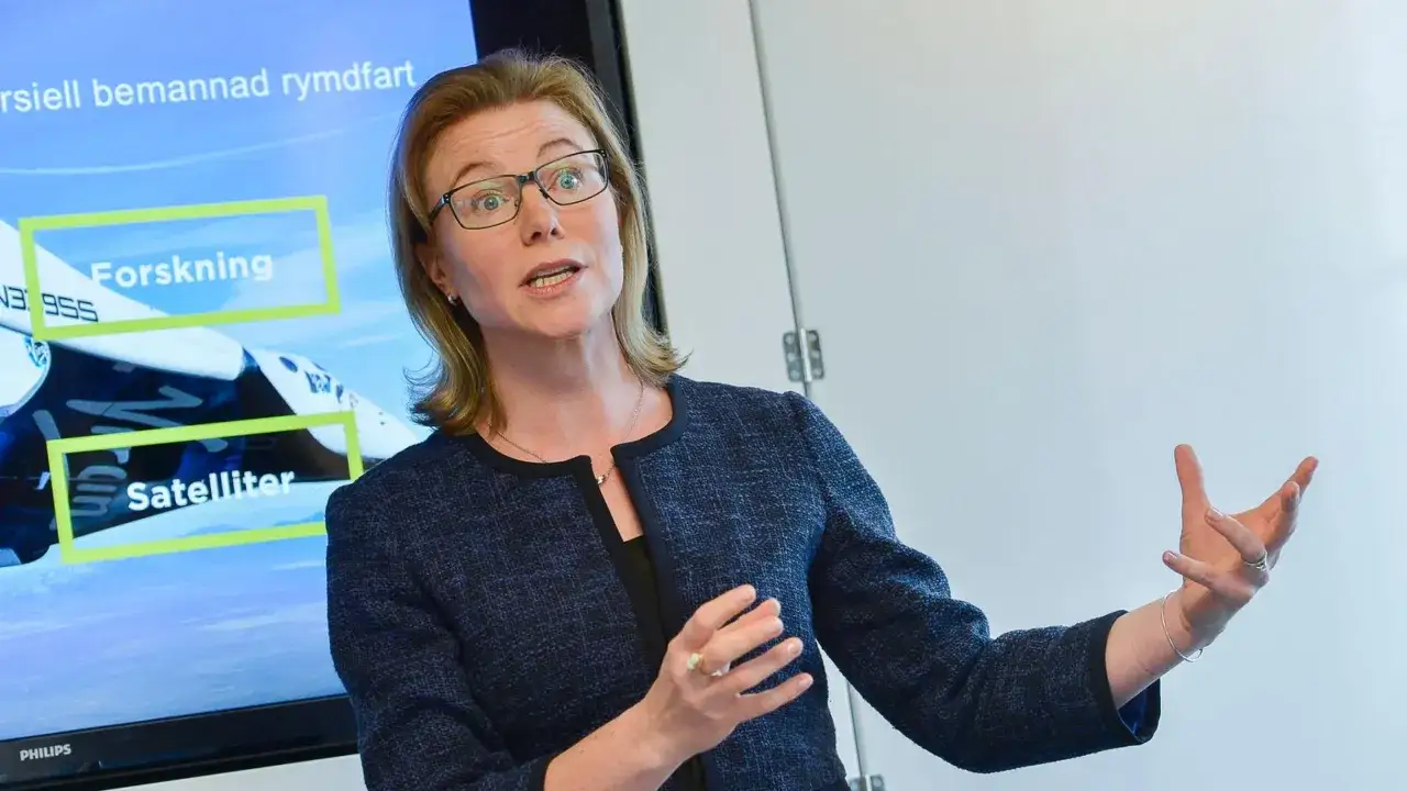Karin Nilsdotter, med glas&ouml;gon, gestikulerar framf&ouml;r en sk&auml;rm som visar 