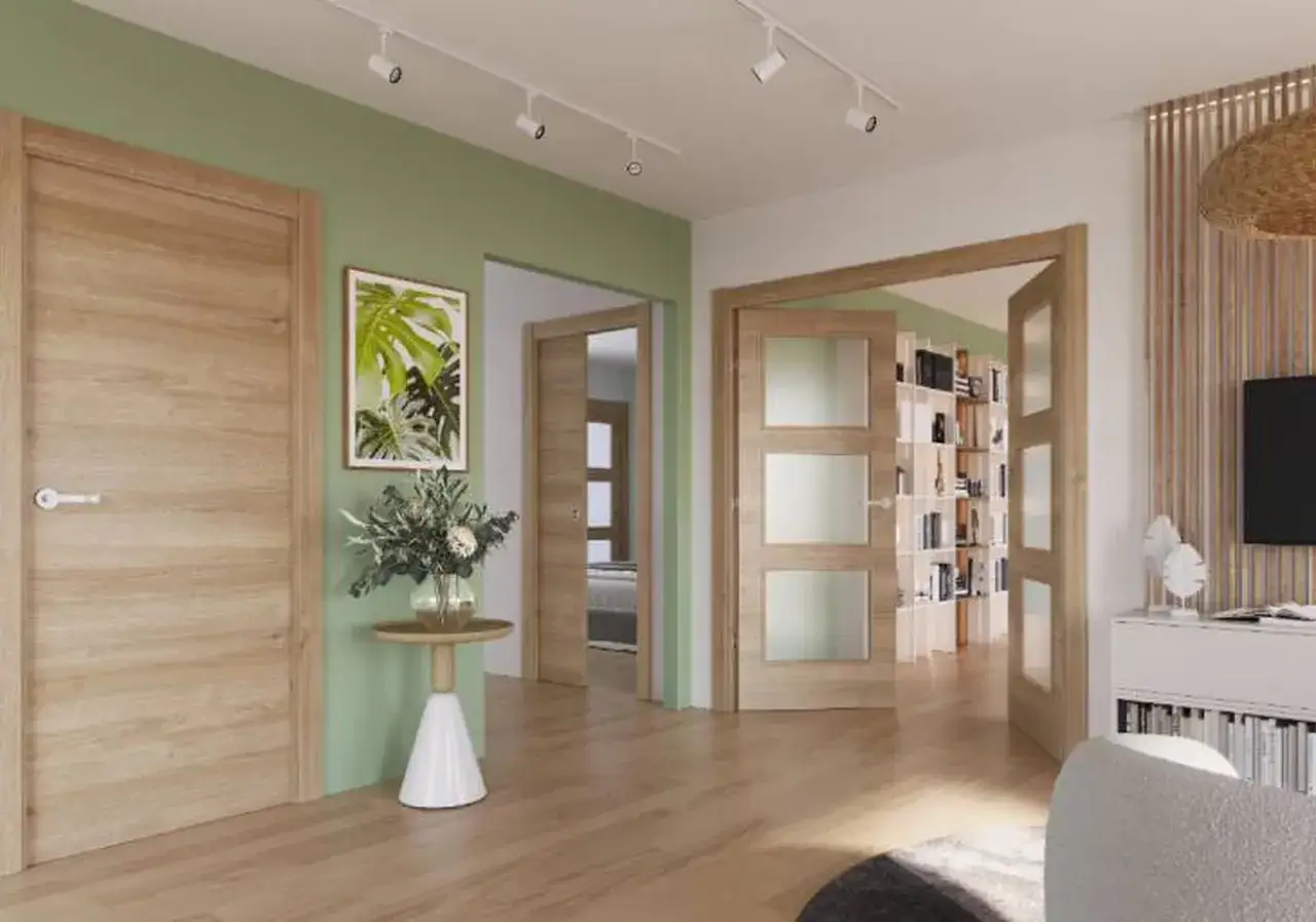 Un pasillo con paredes verde menta y puertas de roble. Una puerta doble con paneles de vidrio se abre a una estanter&iacute;a llena de libros.