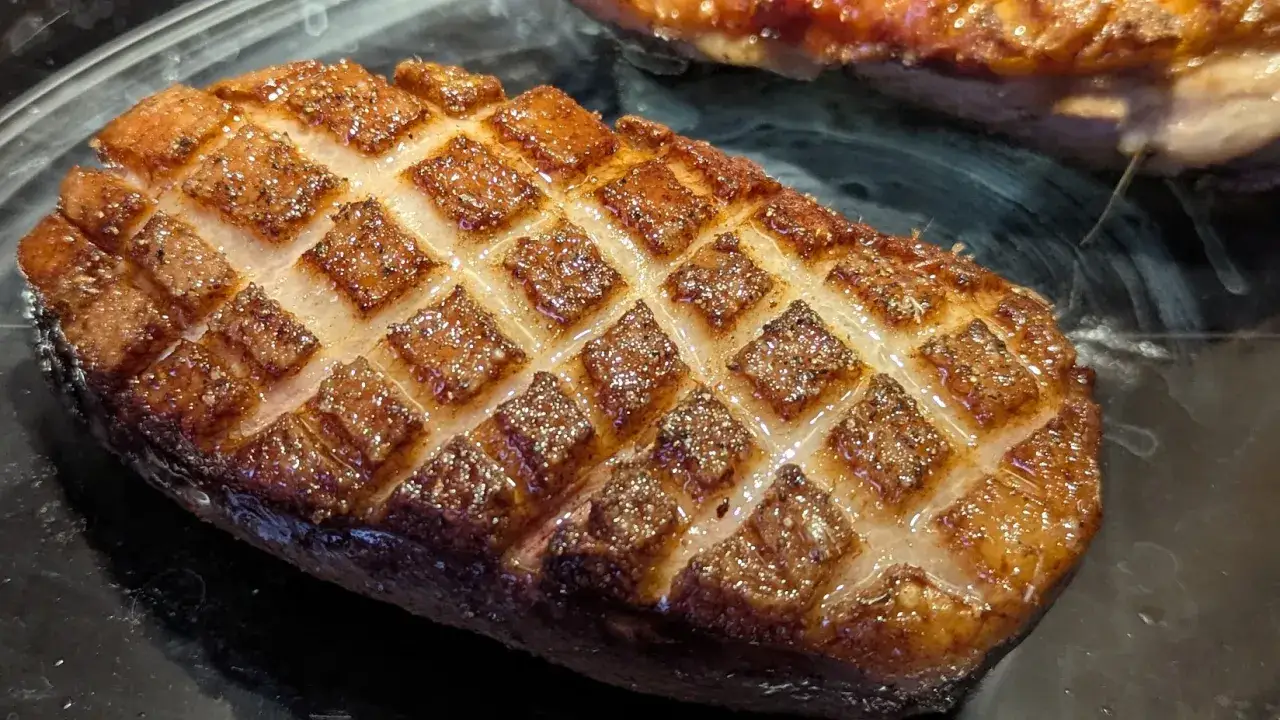 Un magret de canard grillé, la peau quadrillée et dorée, prêt à être dégusté.