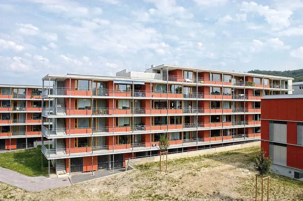Immeuble moderne de logement étudiant suisse aux façades orange vif, balcons et grandes fenêtres.