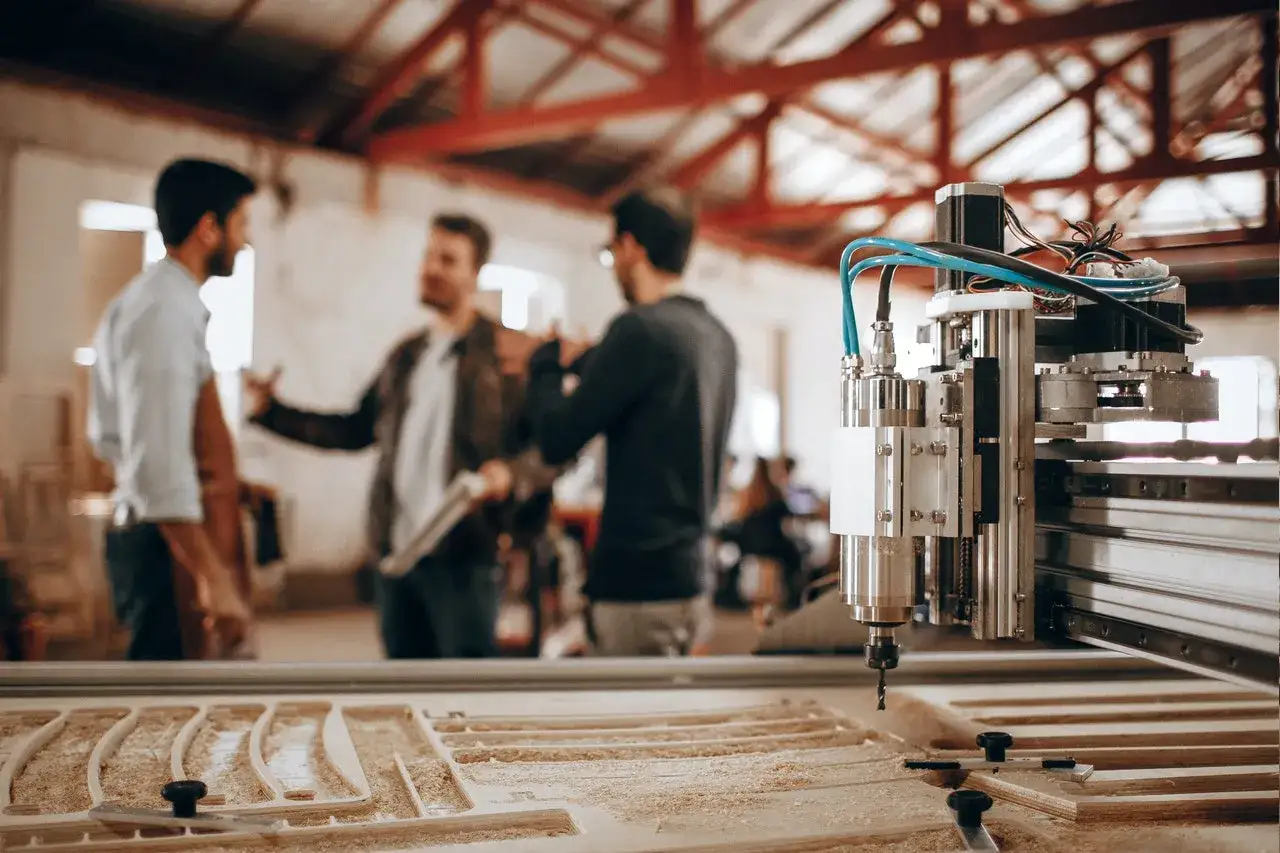 Dział utrzymania ruchu omawia projekt z operatorami przy maszynie CNC.