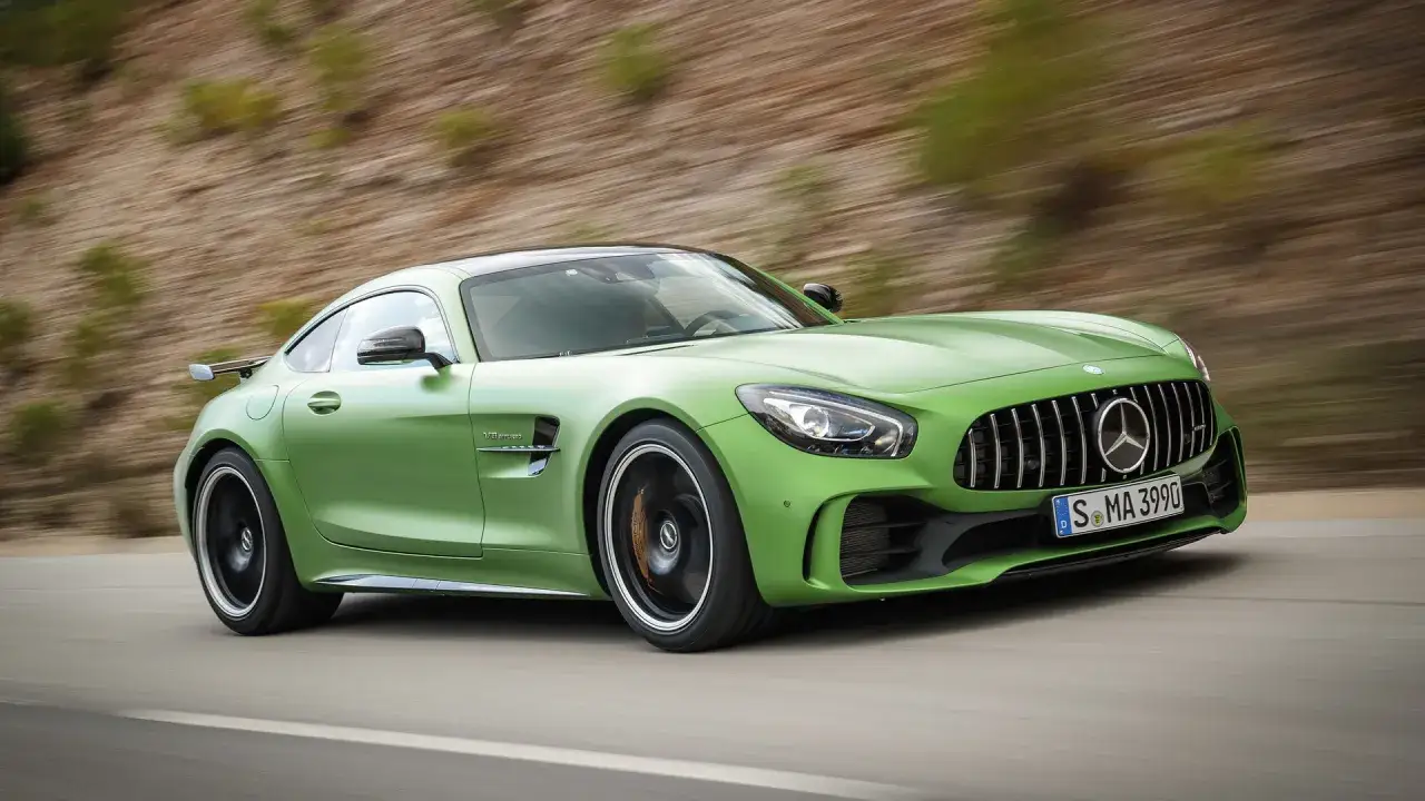 Zielony Mercedes-AMG GTR pędzi po krętej drodze, jego matowe wykończenie lśni w słońcu.