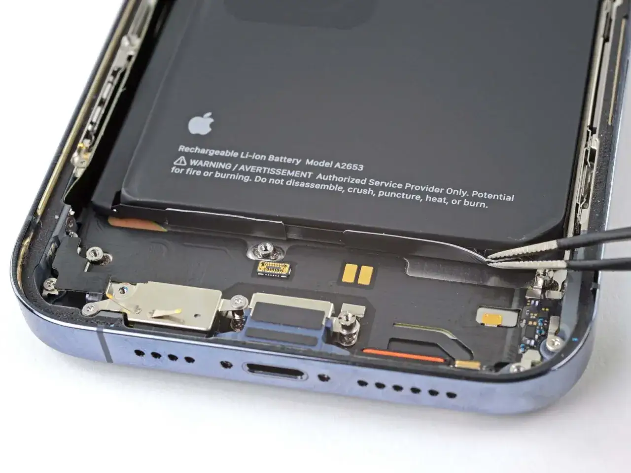 Wymiana baterii iPhone 14 Pro: precyzyjne narzędzia odłączają taśmę baterii.