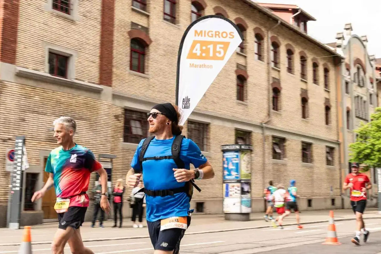 Läufer im Marathon, die sich auf die taper week vorbereiten. Ein Mann in Blau mit Rucksack und ein anderer in buntem Shirt.