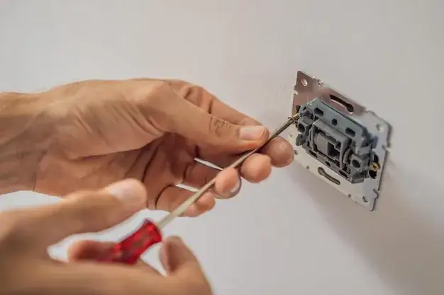 elektryk montujący gniazdko lub włącznik światła
