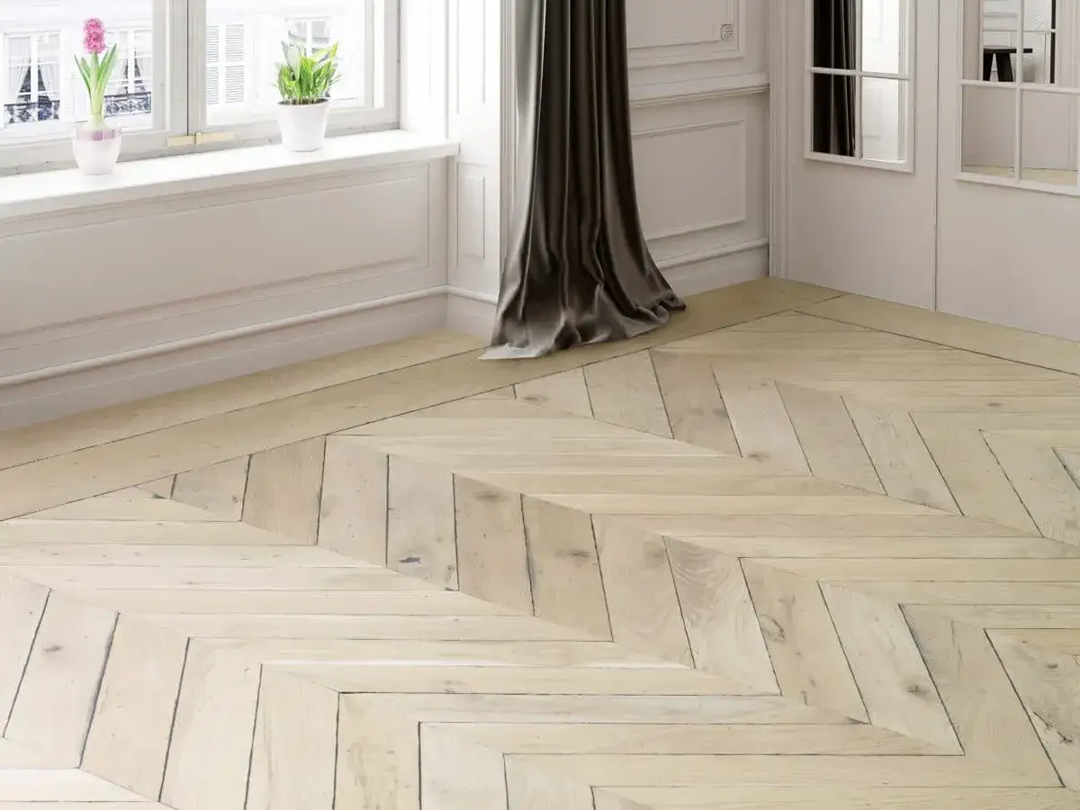 Un élégant parquet point de Hongrie en bois clair, avec des motifs en chevrons qui apportent du caractère à la pièce.
