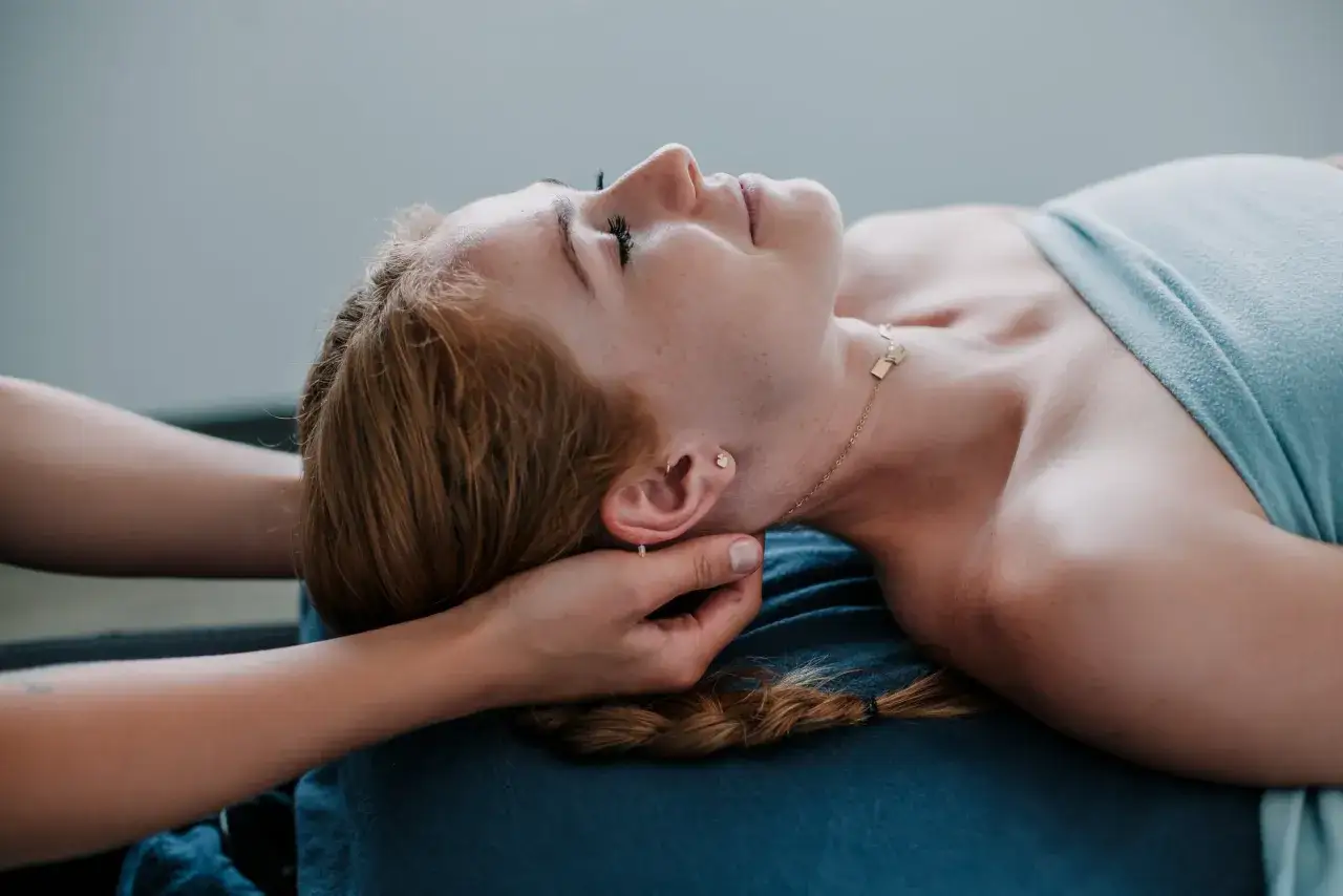 Relaks po masażu głowy. Dłonie terapeuty delikatnie masują skronie, przynosząc ukojenie.