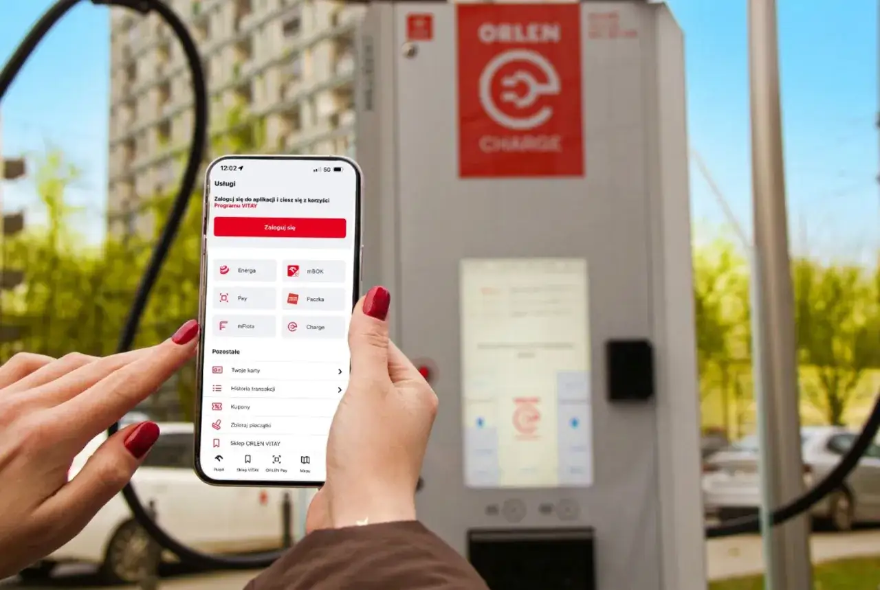 Kobieta używa aplikacji ORLEN do ładowania samochodu elektrycznego przy stacji ORLEN Charge.
