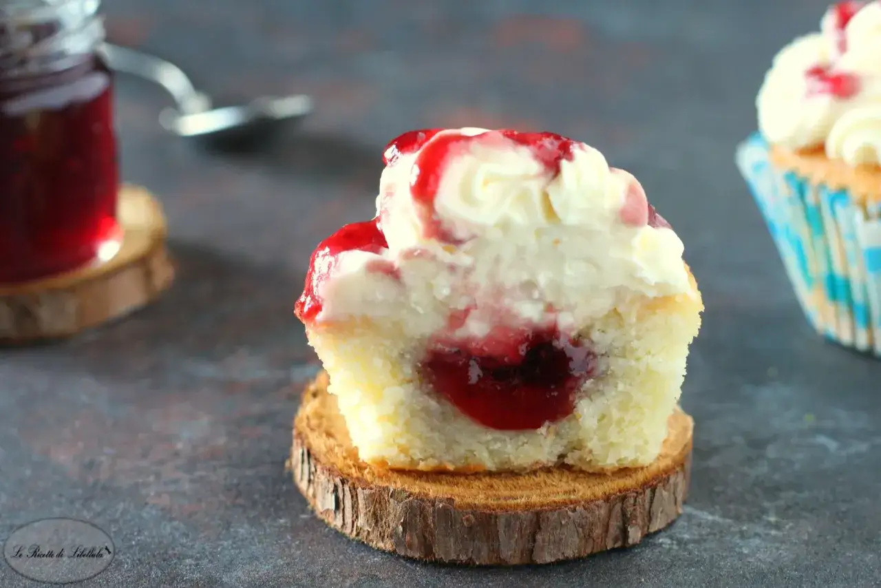 Delizioso cupcake con glassa bianca e ripieno di marmellata rossa, perfetto per la tua prossima ricetta.