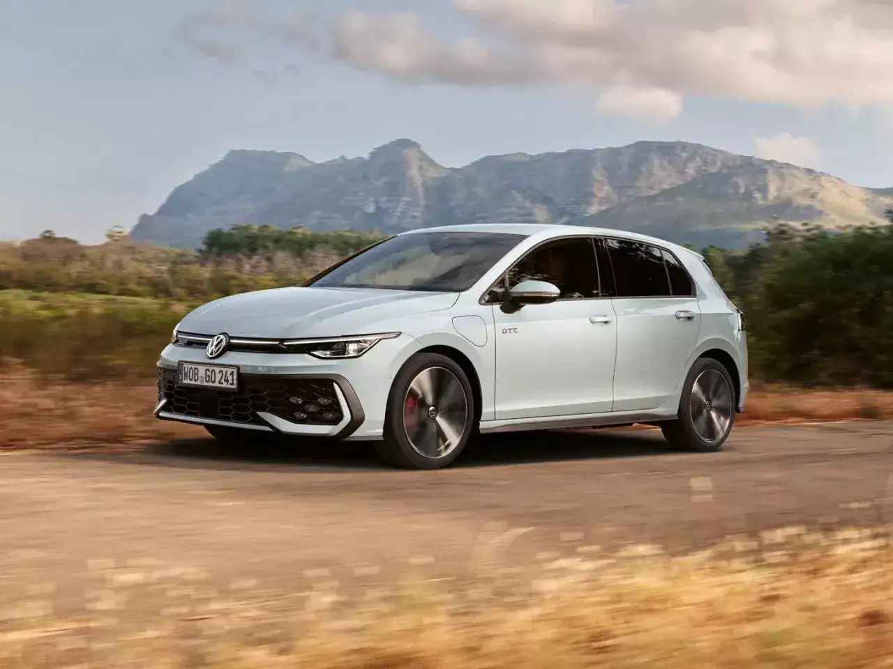 Biały Volkswagen Golf GTE przemierza malowniczą drogę wśród wzgórz.