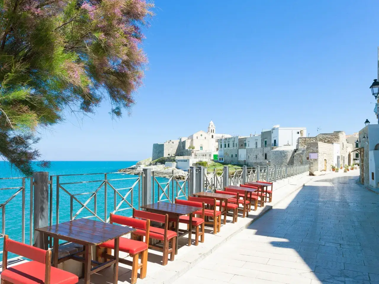 Tavoli rossi con vista mare a Vieste, perfetti per godersi i migliori ristoranti.