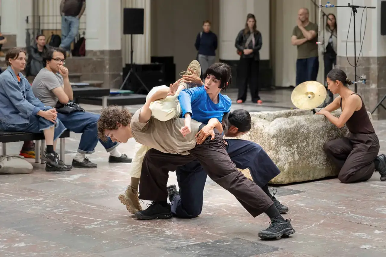 Performance de danse contemporaine, Tarek Atoui chorégraphie un ballet humain intense. Des danseurs s'entrelacent, créant des formes dynamiques.