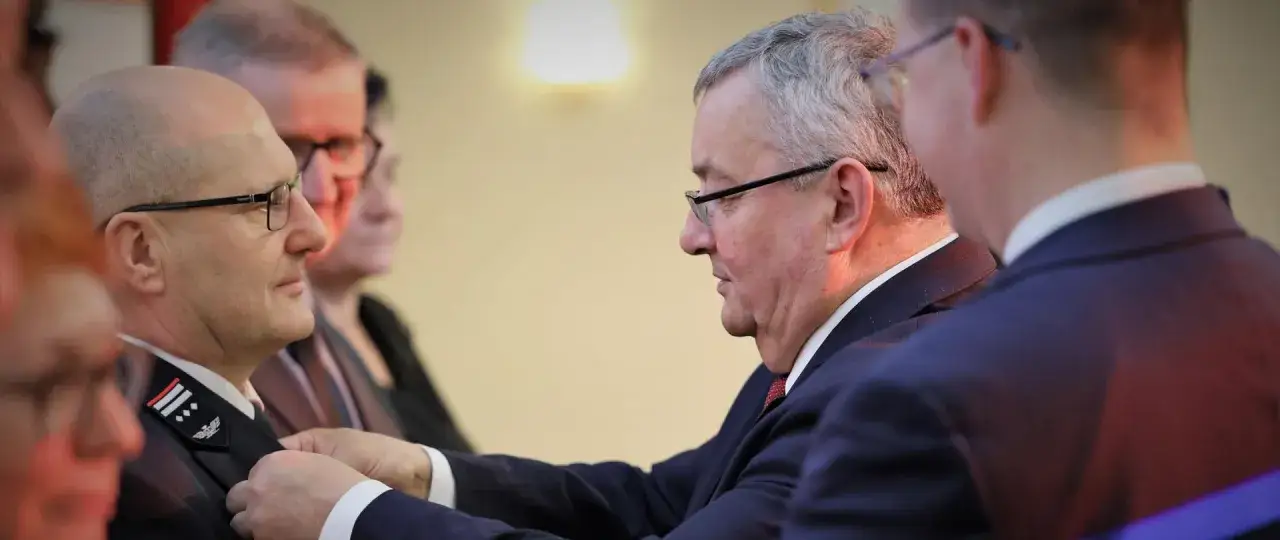 Uroczyste wręczenie odznaczenia mężczyźnie w mundurze, który jest zasłużony dla kolejnictwa.