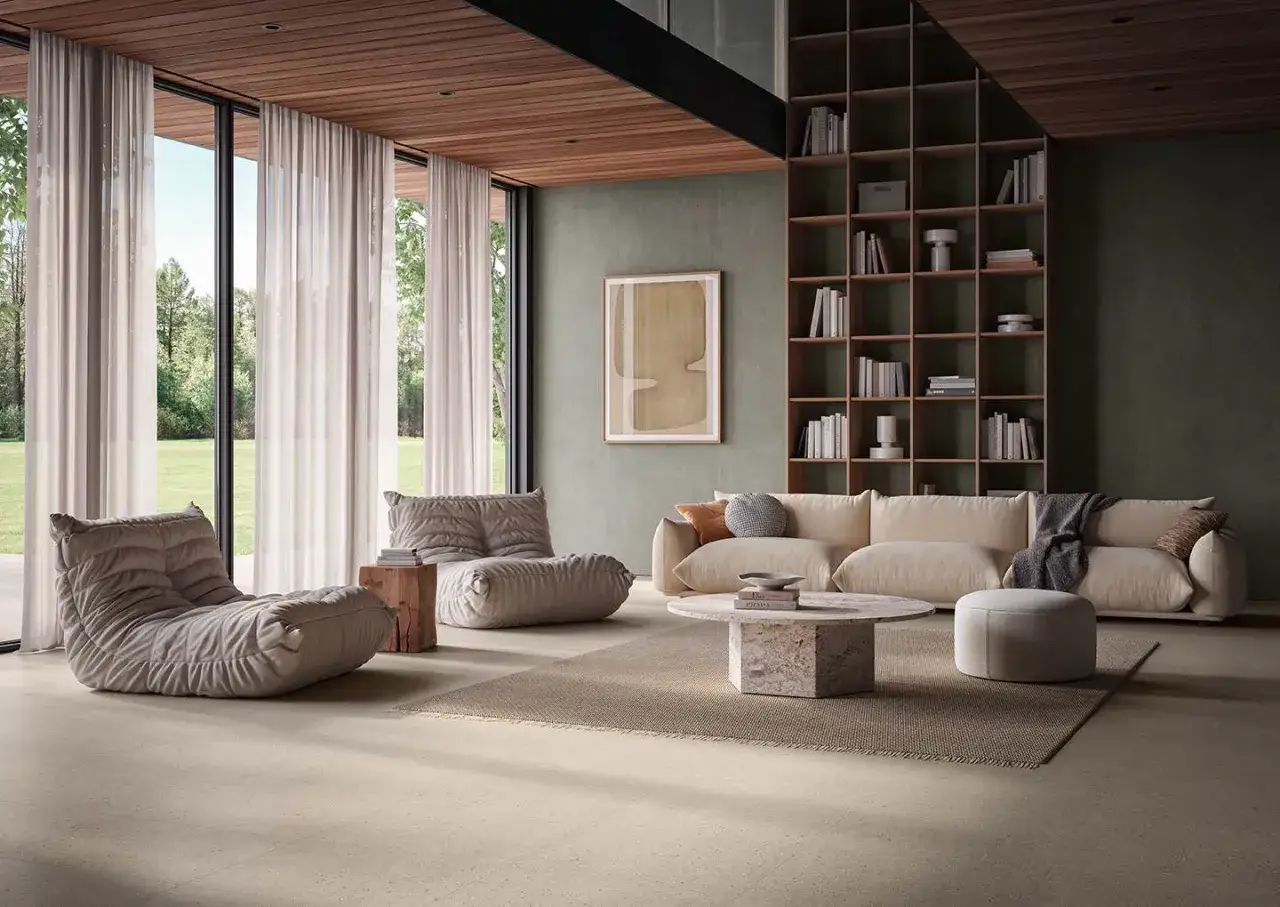 Sal&oacute;n moderno con sof&aacute;s beige, mesa de centro de m&aacute;rmol y estanter&iacute;as. El **revestimiento del suelo** de tonos claros complementa la decoraci&oacute;n.