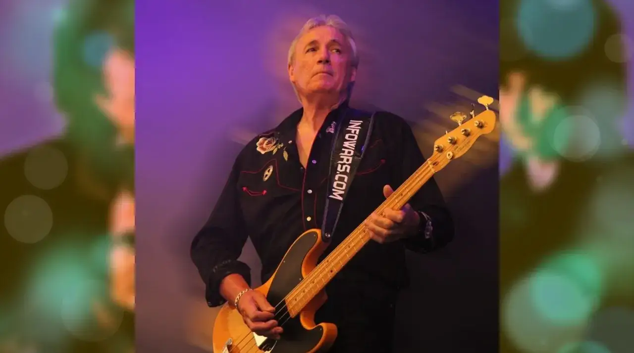 Nick Simper, Bassist, spielt auf einer E-Gitarre. Sein schwarzes Hemd ist mit Rosen bestickt.