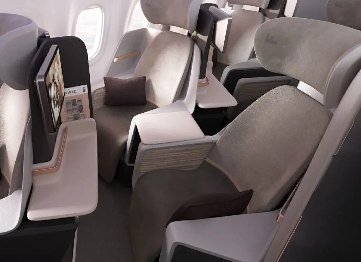 Moderne Flugzeug Sitze in einer Business- oder First-Class-Kabine. Die Sitze sind aus grauem Stoff, mit integrierten Bildschirmen und kleinen Tischen.