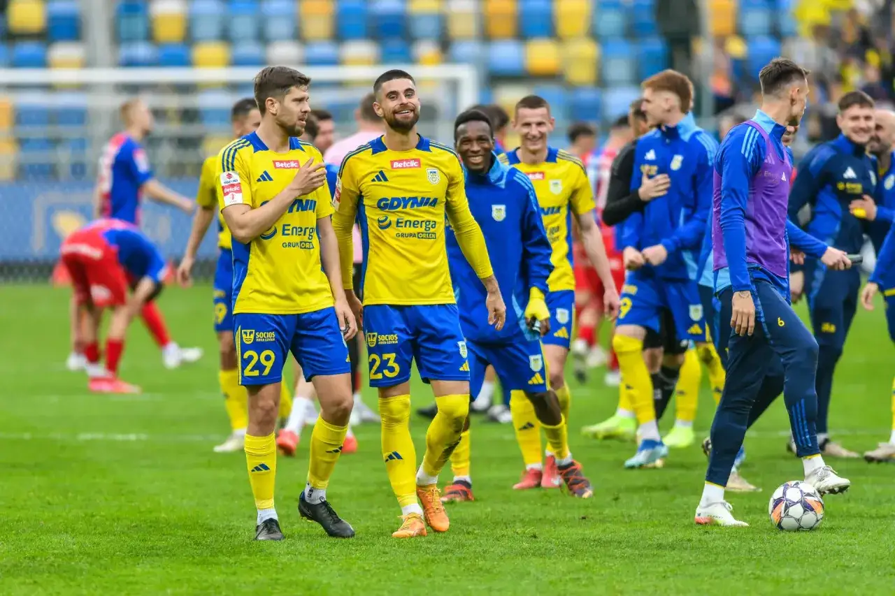 Piłkarze Arki Gdynia w żółtych strojach, gotowi na nowe wyzwania i transfery.