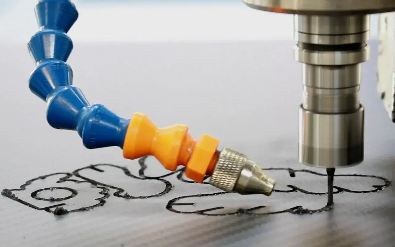 CNC-Fr&auml;ser bearbeitet eine Carbonplatte, wobei ein K&uuml;hlmittelstrahl die Schnittkante k&uuml;hlt.