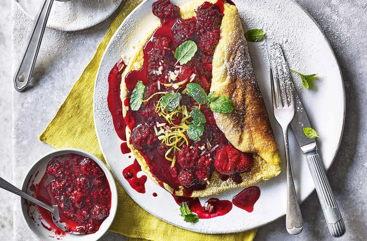Omlet fit z malinami i miętą, posypany cukrem pudrem. Pyszne i zdrowe śniadanie.