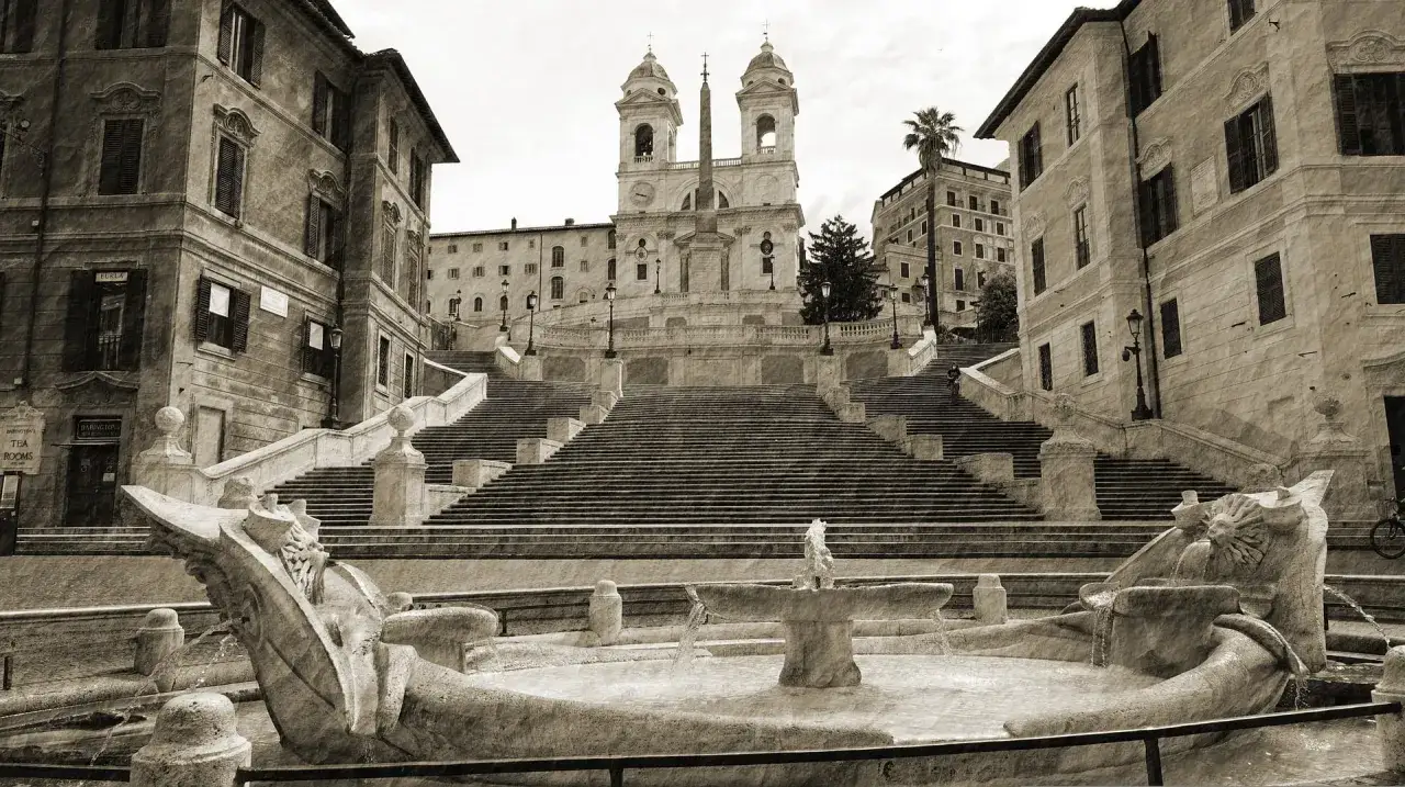Fontana della Barcaccia e scalinata di Trinità dei Monti, un luogo iconico. Si chiama Piazza di Spagna per la vicinanza all'ambasciata spagnola.