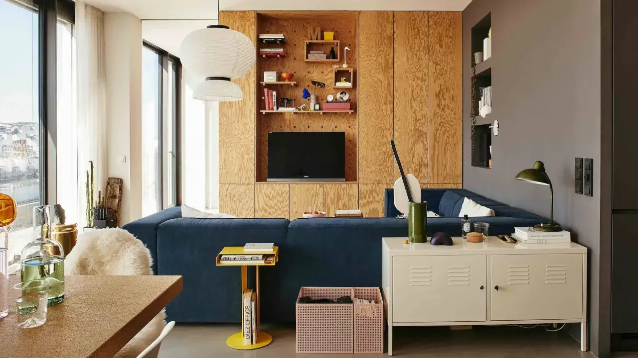 Un salon moderne avec un canapé bleu, des étagères en bois et des idées pour comment agrandir une pièce.