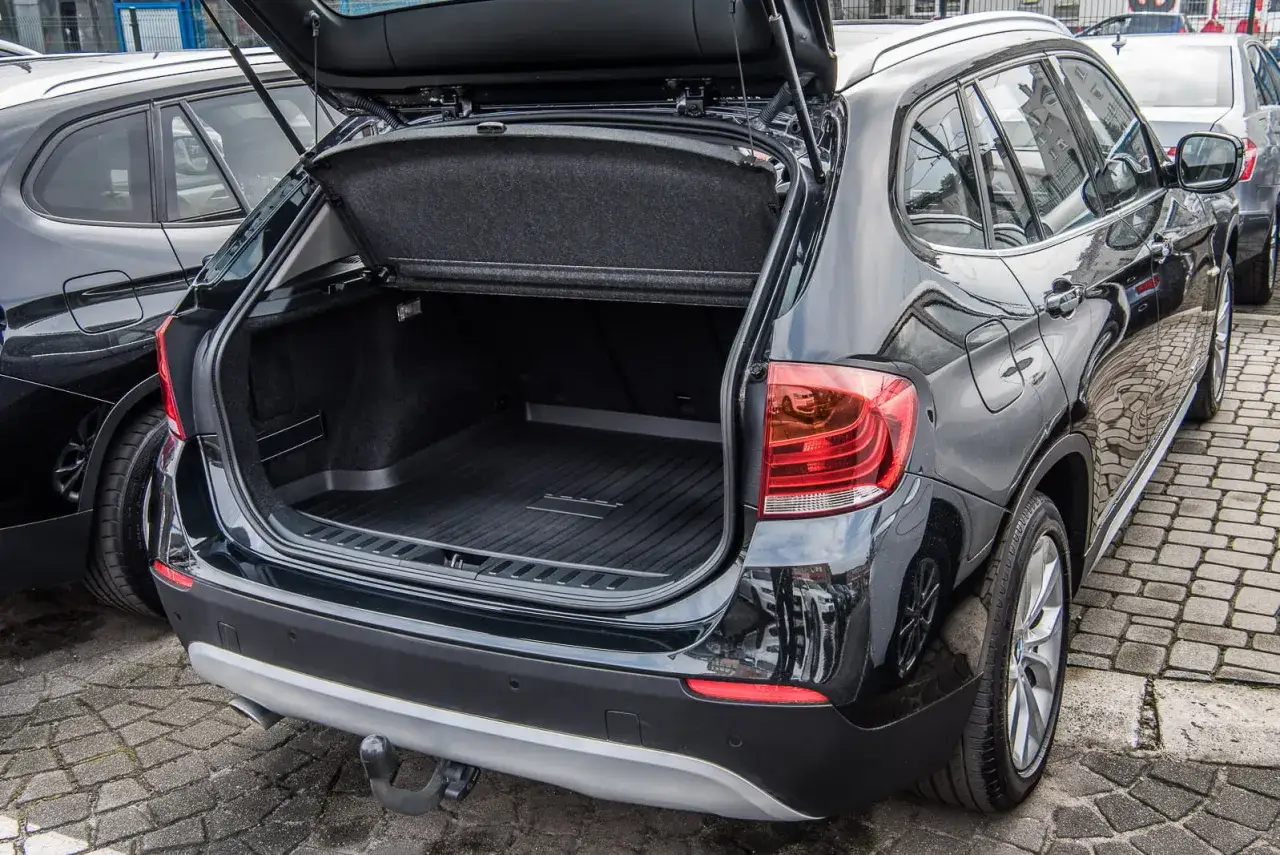 Czarne BMW X1 E84 z otwartym bagażnikiem, gotowe na podróż.