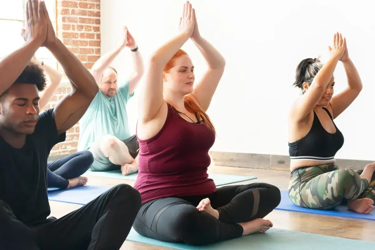 M&auml;nniskor sitter i lotusst&auml;llning p&aring; yogamattor, en del av en resa mot yin yoga viktminskning.