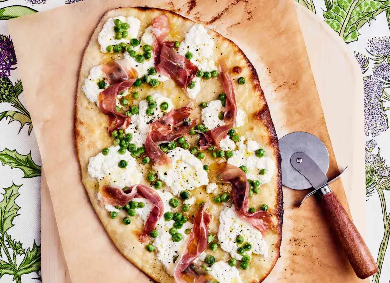 Pyszna pizza rzymska z ricottą, groszkiem i szynką parmeńską, gotowa do pokrojenia.