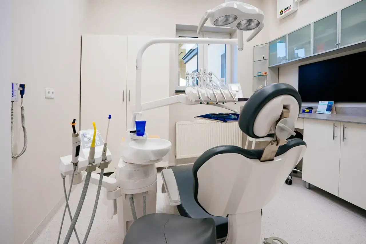 Nowoczesny gabinet stomatologiczny z fotelem, unitem i lampą zabiegową.