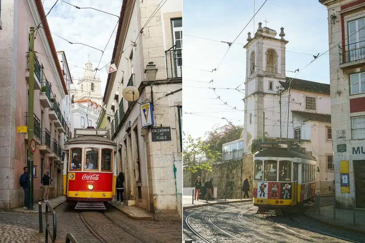En klassisk lissabon sp&aring;rvagn p&aring; kullerstensgator, med gamla byggnader och kyrktorn i bakgrunden.
