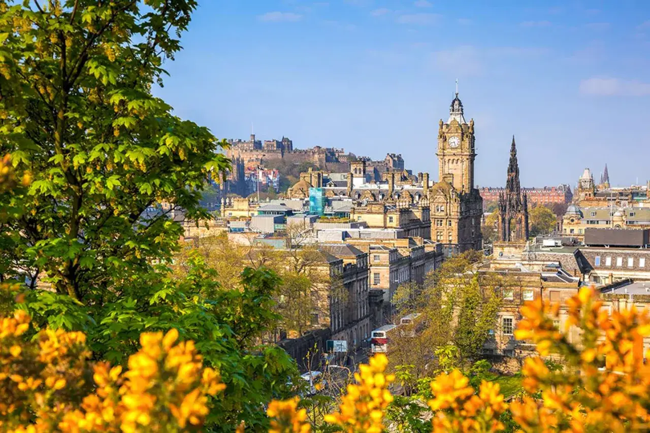 Edinburgh im Frühling: blühende Bäume und die Skyline mit Schloss und Uhrturm. Die beste Reisezeit für dieses Panorama.