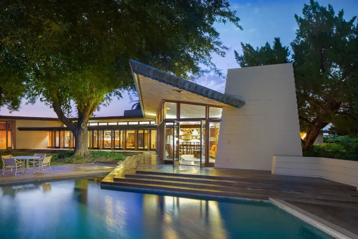 Magnifique piscine refl&eacute;tant le ciel cr&eacute;pusculaire devant une maison aux lignes audacieuses, une des structures con&ccedil;ues par Frank Lloyd Wright.