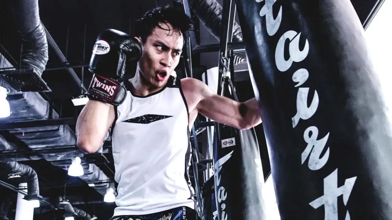 A boxer trains intensely, focusing on his boxing breathing as he punches a heavy bag.