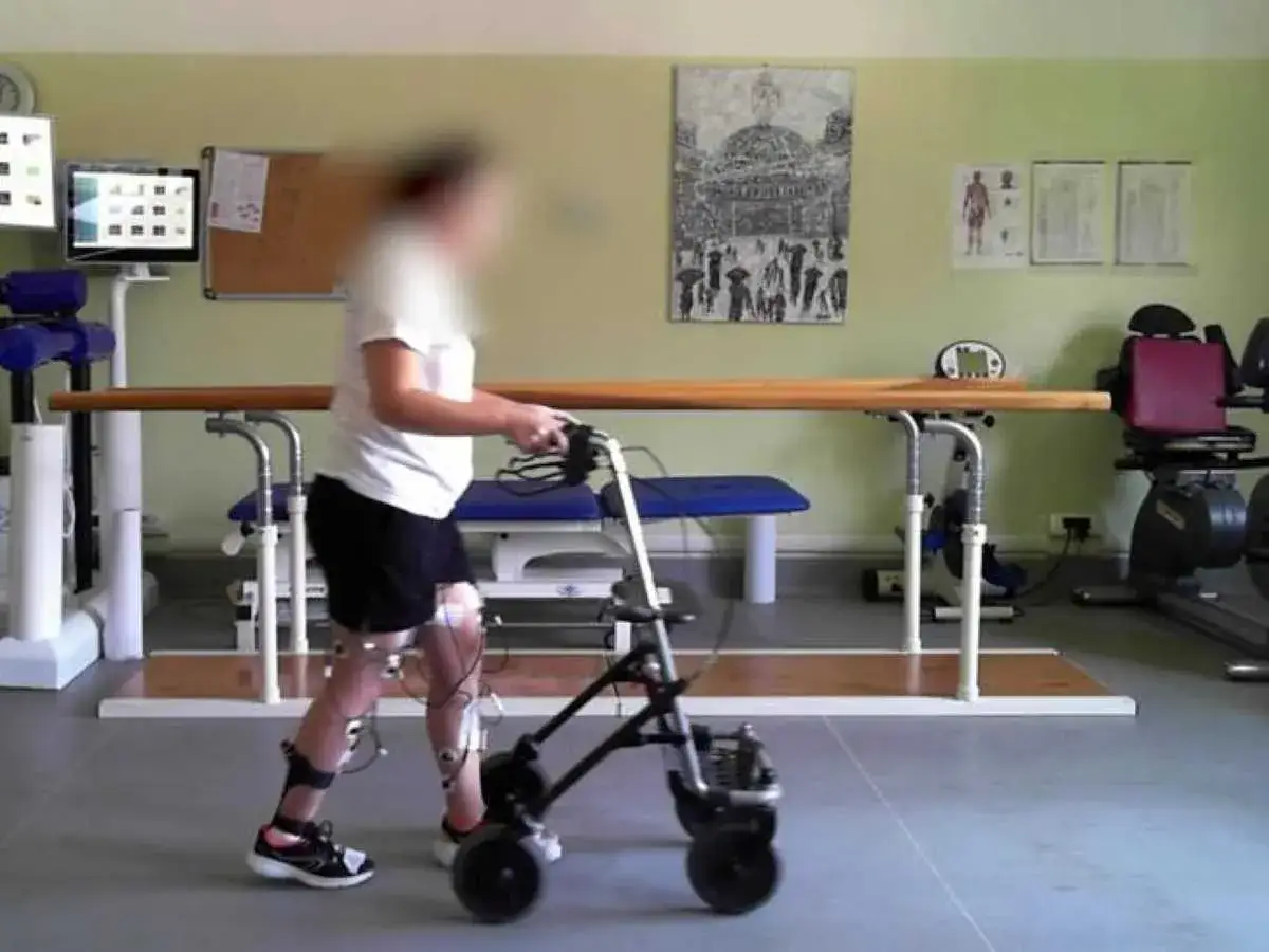 Persona con neurostimolatore midollare invalidit&agrave;, in riabilitazione con deambulatore e sensori alle gambe.