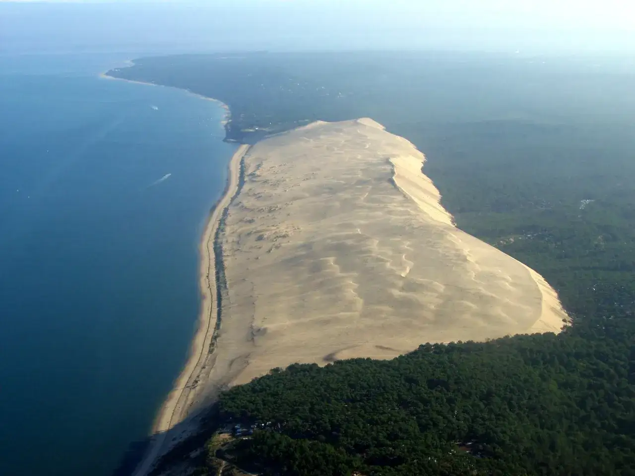 Vista aérea de la duna de Pilat, la duna más alta de Europa, en Las Landas, Francia. El mar azul contrasta con la arena dorada y el verde de los pinos.