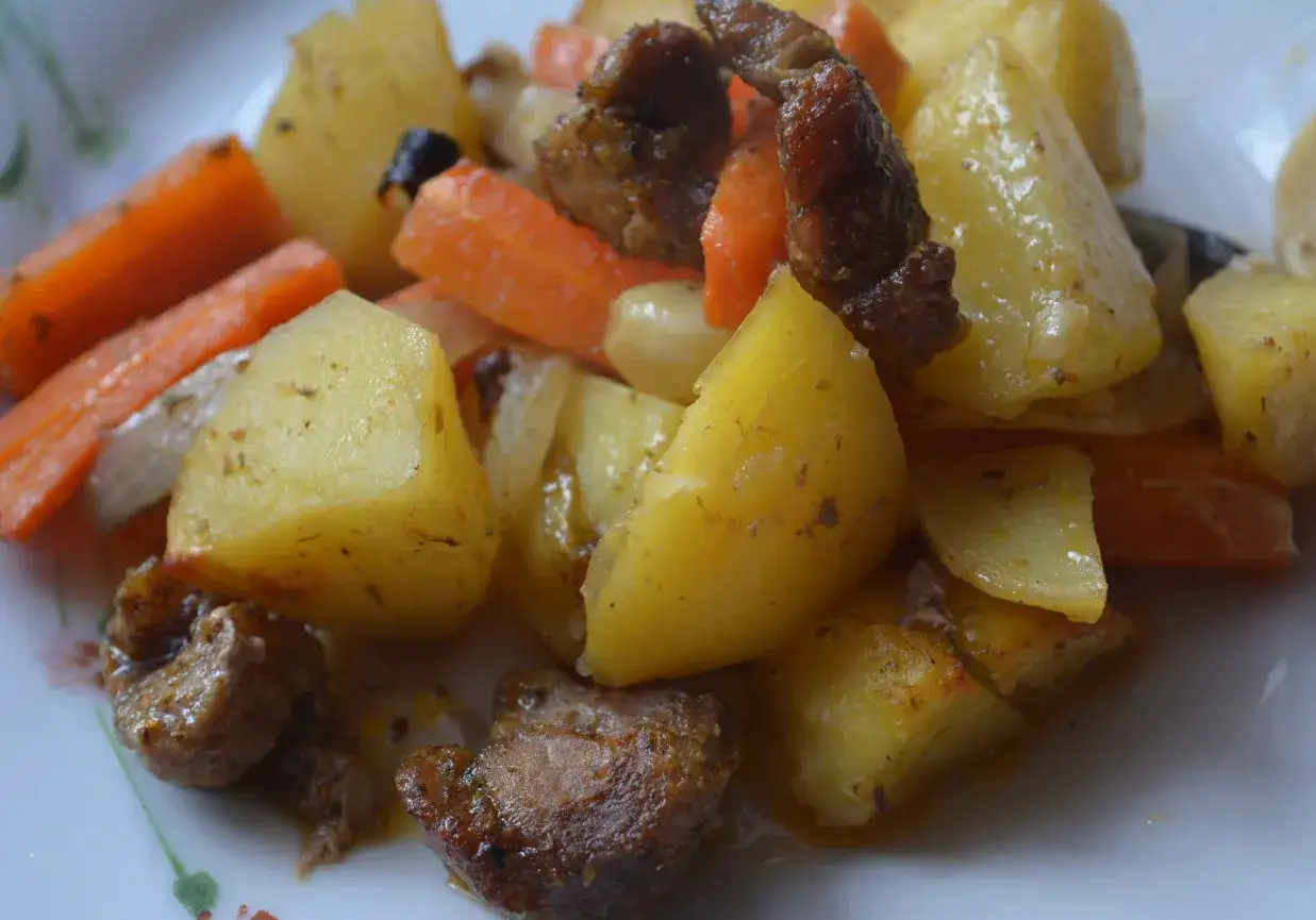 Pieczona łopatka wieprzowa na obiad z ziemniakami i marchewką, danie pachnące ziołami, gotowe do podania.
