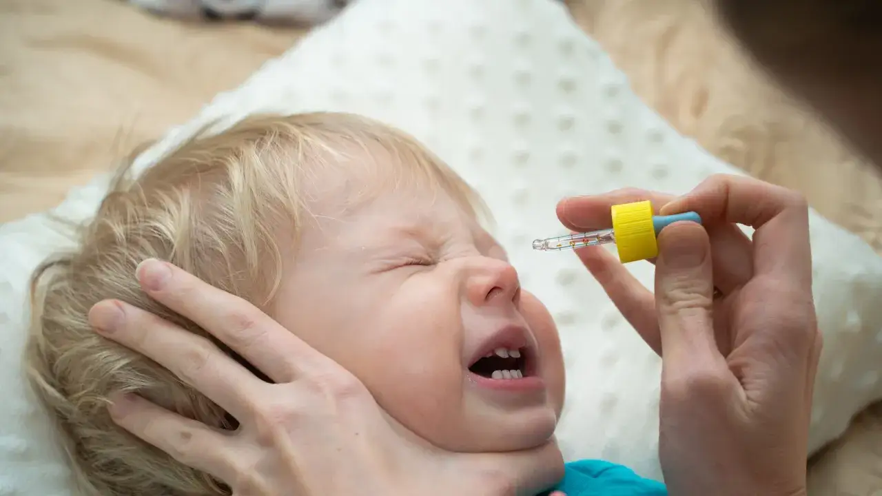 Ein Baby weint, während ihm Nasentropfen verabreicht werden.