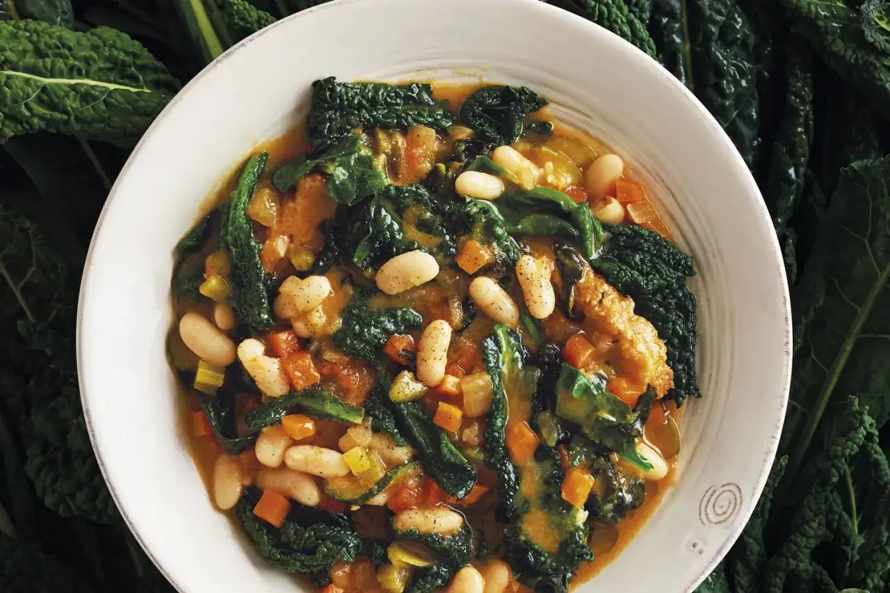 Un piatto di cavolo nero, fagioli cannellini e verdure, un classico esempio di cosa mangiare in Toscana per un pasto nutriente e saporito.