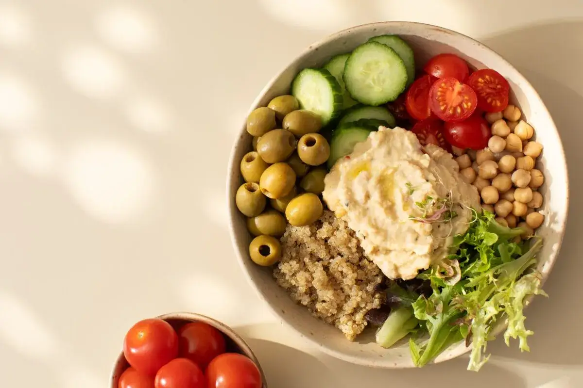 Miseczka pełna zdrowia: hummus, kasza, oliwki, pomidorki, ogórek i ciecierzyca. Ciecierzyca właściwości odżywcze w pysznej odsłonie.