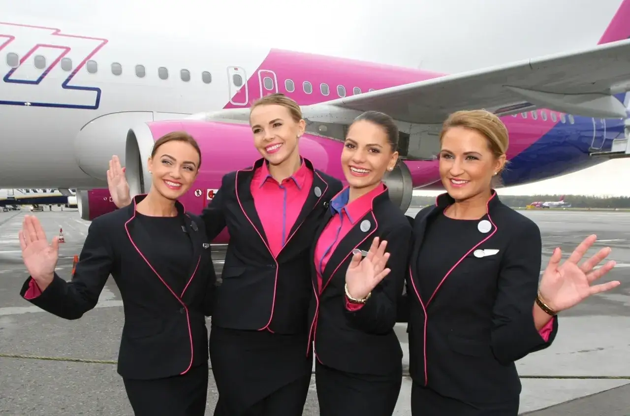 Cztery stewardessy Wizz Air pozują przed samolotem. Ciekawe, ile zarabia stewardessa Wizz Air?