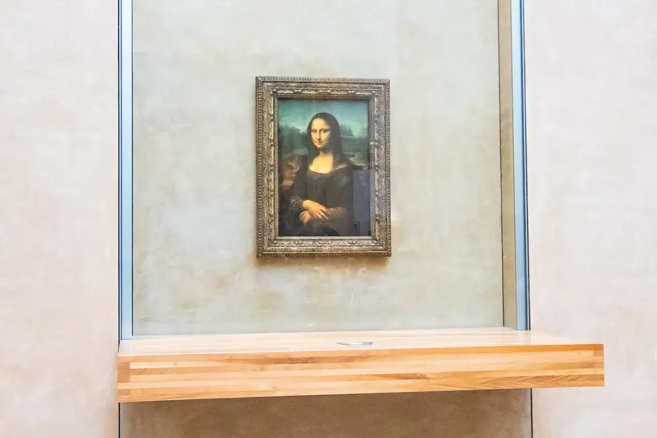 Mona Lisa tavla, inkapslad bakom glas, hänger på en ljus vägg.