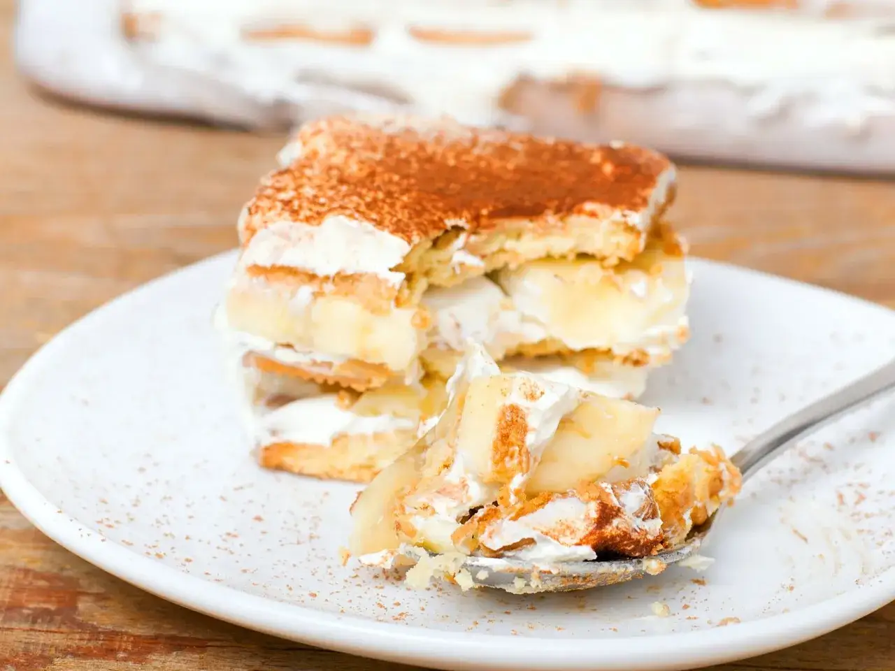 Pyszne ciasto bez pieczenia z bananami i kremem, posypane kakao. Idealne na deser.