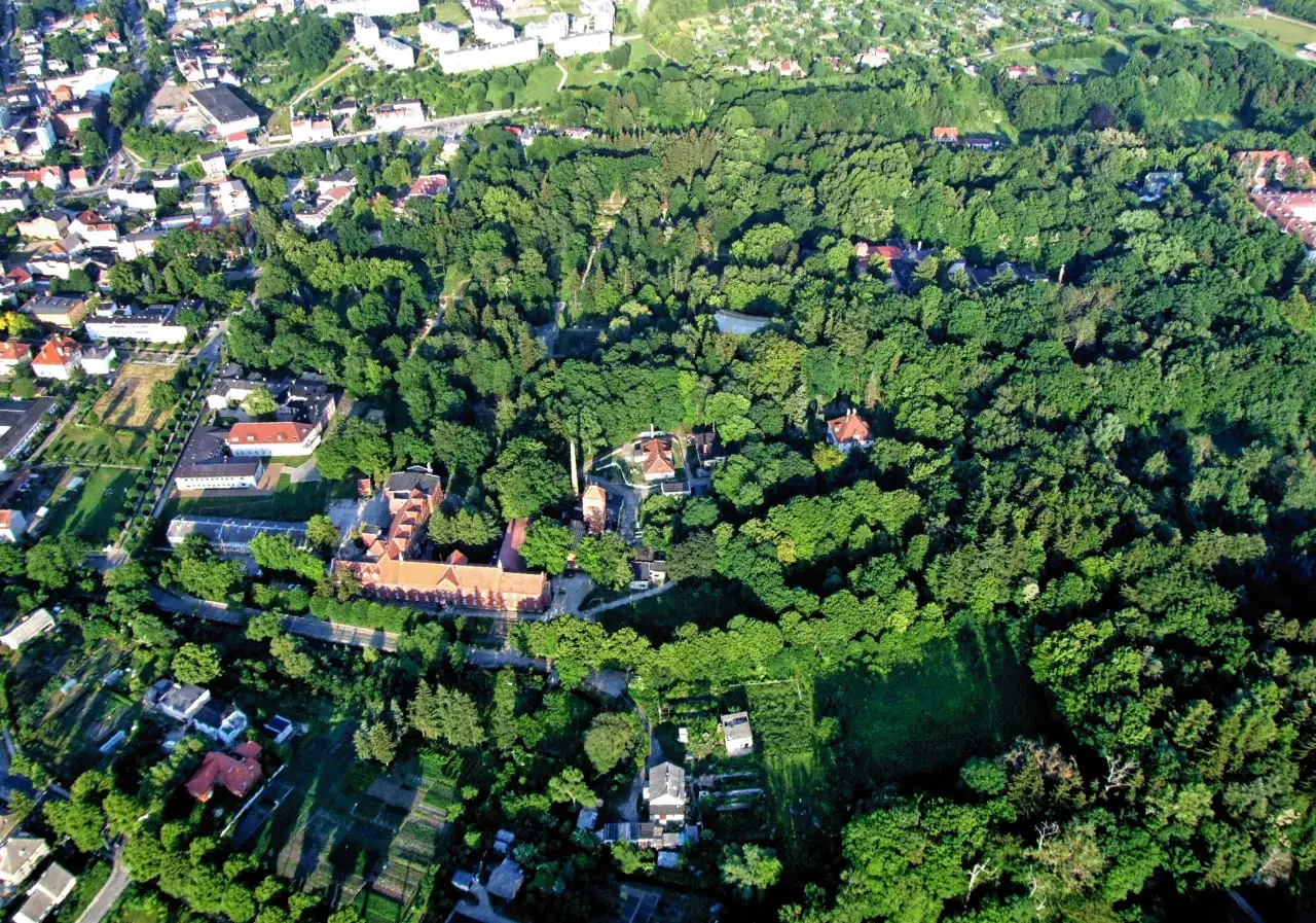 Widok z lotu ptaka na Połczyn-Zdrój, miasto otoczone bujną zielenią. Widać zabudowania, drogi i rozległe tereny leśne.