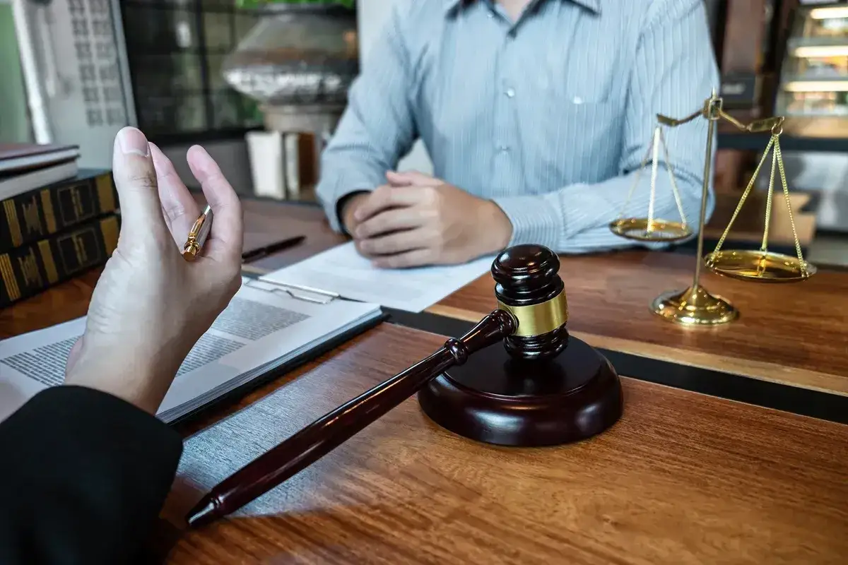 Rozmowa o spadku z dobrodziejstwem inwentarza. Na stole młotek sędziowski, waga sprawiedliwości i dokumenty.