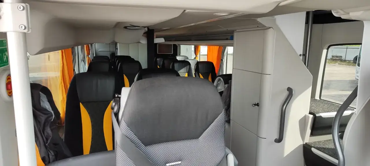 Wnętrze autokaru z czarnymi i żółtymi siedzeniami. Zastanawiasz się, ile kosztuje wynajem autokaru?