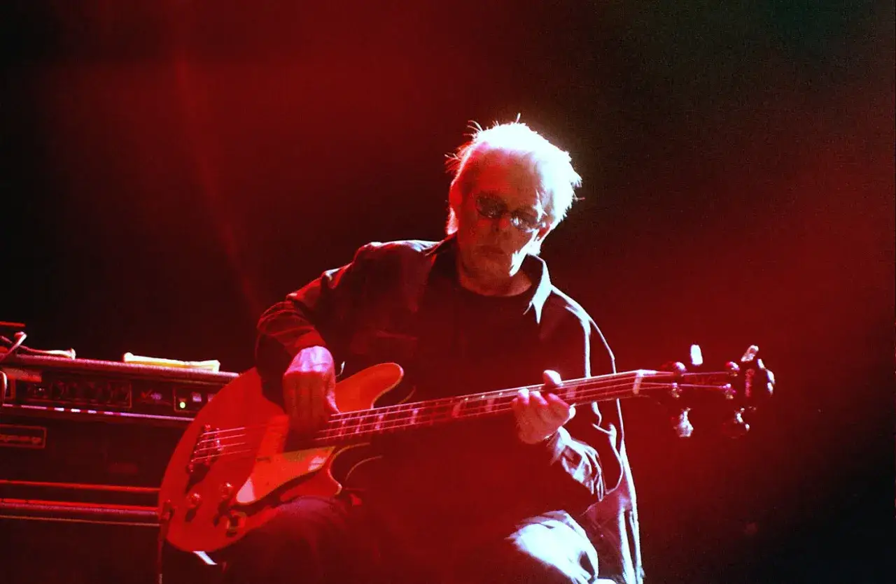 Jack Casady spielt auf seiner roten E-Gitarre, beleuchtet von rotem B&uuml;hnenlicht.