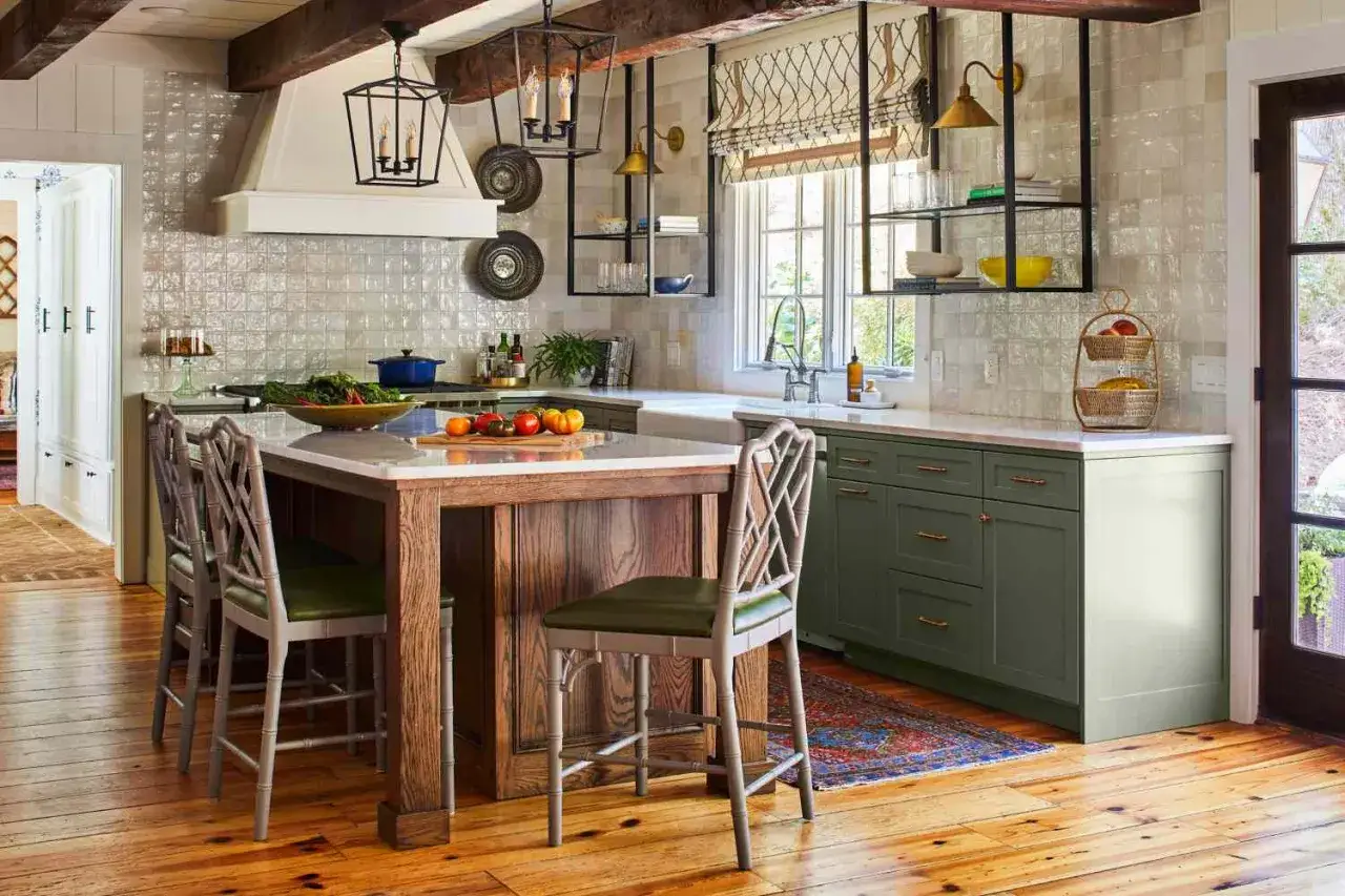 Cuisine r&eacute;nov&eacute;e dans un style rustique, avec un &icirc;lot central en bois, des armoires vertes et des luminaires lanternes.