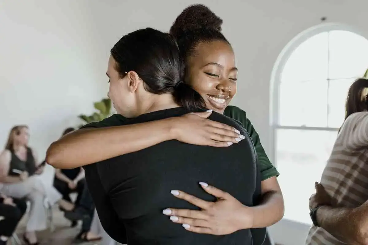 Zwei Frauen umarmen sich herzlich. Ihre Gesichter strahlen Glück aus, was die schönen Eigenschaften von Freundschaft widerspiegelt.