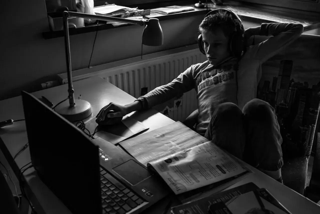 Chłopiec w słuchawkach pochłonięty grą na komputerze. To jego autoportret fotografia, uchwycony w chwili skupienia.