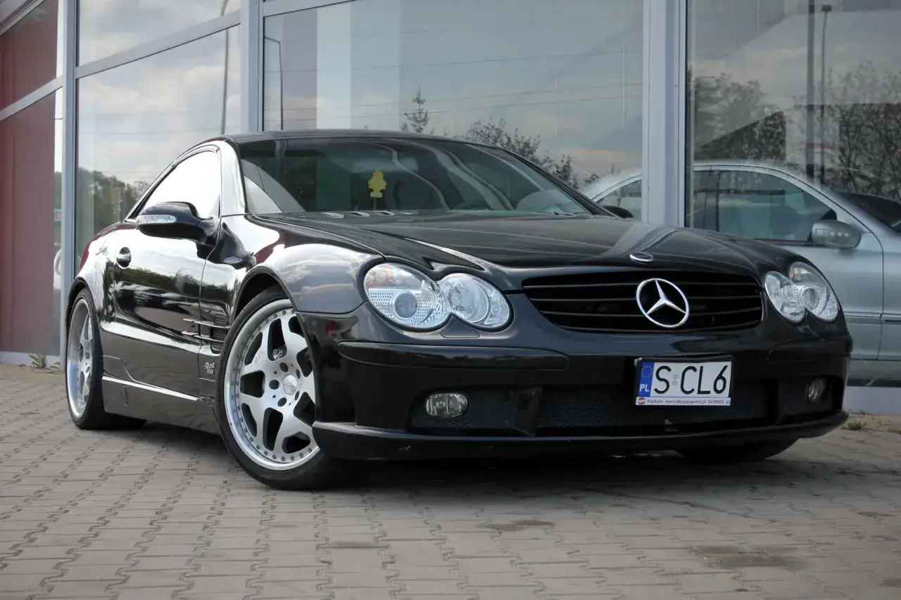 Czarny Mercedes SL500 lśni na tle szklanej fasady.